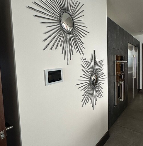 Smart lighting control keypad integrated beside decorative sunburst mirrors