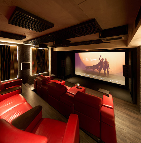 Side view of private cinema with red seating, controlled lighting and acoustic panels