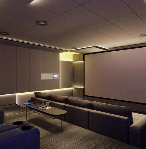 Media room arranged for cinema viewing with modular seating and illuminated wall panels
