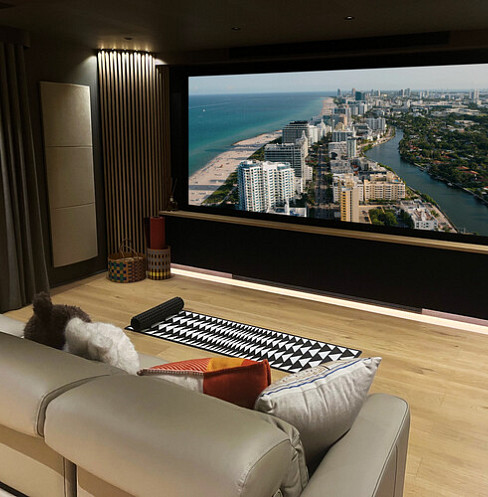 Calm home cinema with large projection screen, soft lighting and tiered lounge seating