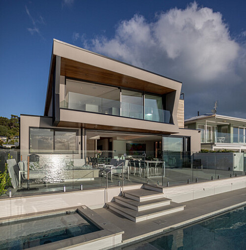 Rear exterior of coastal smart residence with pool, outdoor dining and automated systems