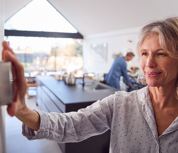 elderly woman using smart thermostat