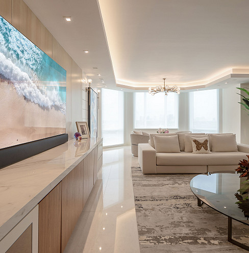 Salón diáfano frente al mar con un televisor de gran tamaño y un sistema audiovisual oculto