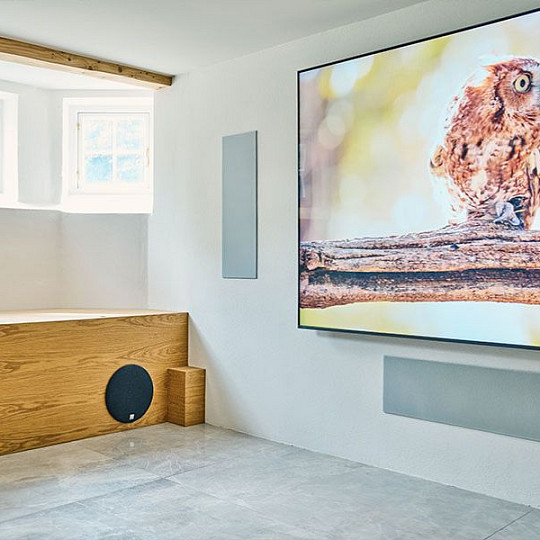 Wall-mounted TV with concealed DALI speakers and subwoofer in a dedicated home cinema