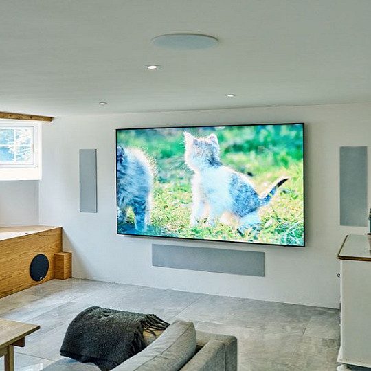 Dedicated home cinema with wall-mounted TV, architectural speakers and hidden AV equipment