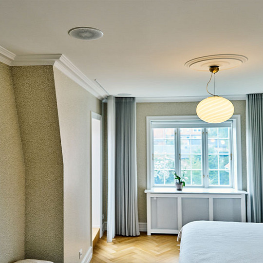 Bedroom with a discreet DALI in-ceiling speaker integrated above the window