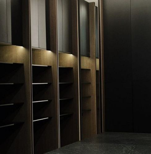 Walk-in wardrobe with concealed integrated lighting and dark fitted cabinetry