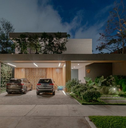 Entrada y garaje de una vivienda inteligente contemporánea iluminados mediante un sistema de iluminación exterior automatizado