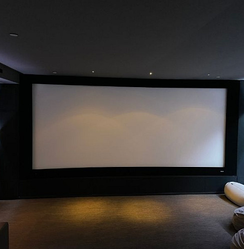 Large projection screen at the front of the dedicated home cinema