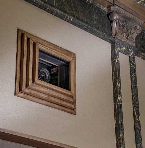 Cinema projector lens concealed within a decorative architectural wall panel