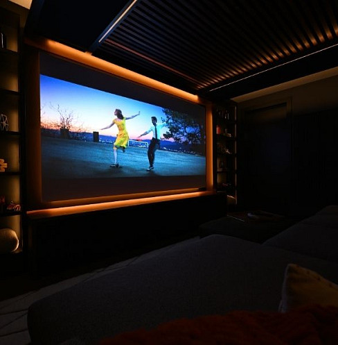 Family home cinema with wide projection screen and warm architectural lighting