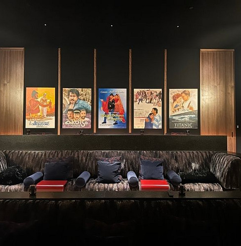 Sala de cine en casa con tecnología oculta, paneles acústicos en las paredes y obras de arte cinematográficas