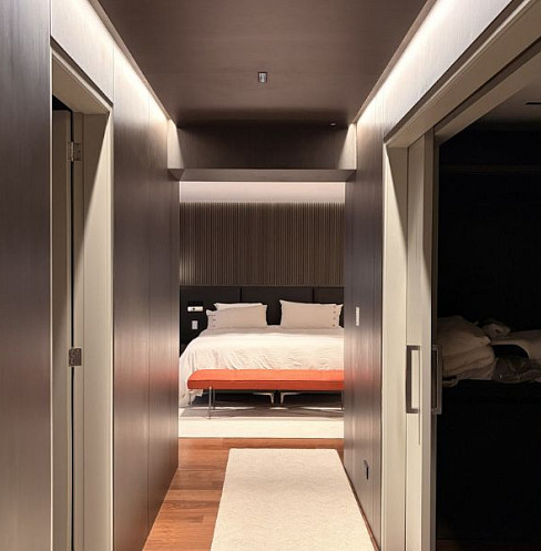 Minimal hallway leading to a bedroom with discreet automated lighting
