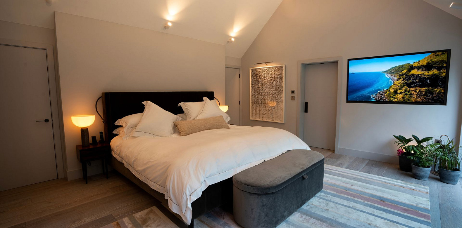 Habitación inteligente con iluminación cálida, televisor montado en la pared y lámparas de noche