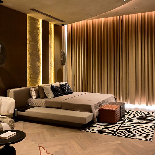 Habitación con una cálida iluminación indirecta y cortinas cerradas para crear un ambiente relajante al atardecer