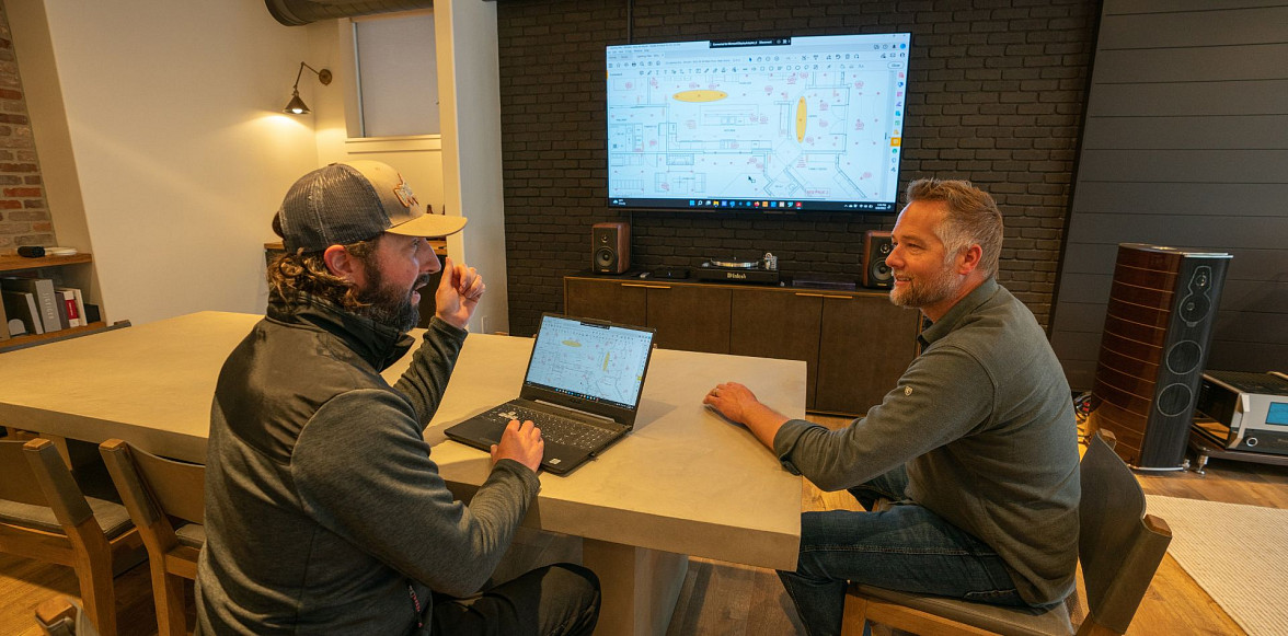 Two smart home professionals reviewing a technical plan on a screen