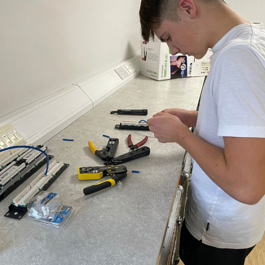 Un aprendiz preparando el cableado de red en un banco de trabajo