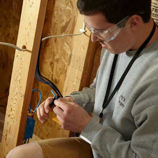 Aprendiz realizando el cableado en el interior de una pared con estructura de madera